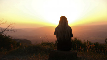 femme devant une ville au coucher du soleil